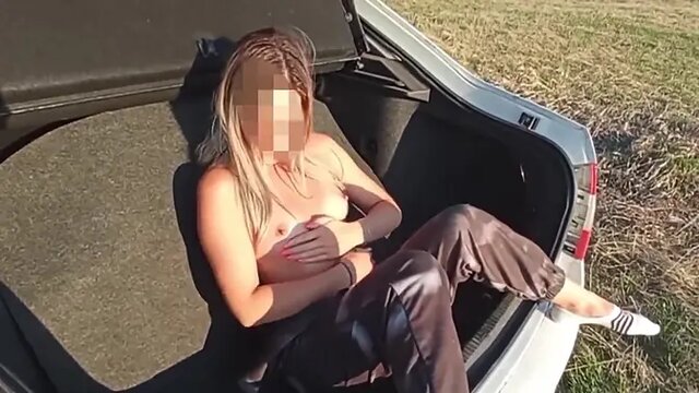 Alluring nude girl poses in a field, flaunting her big ass and fake tits